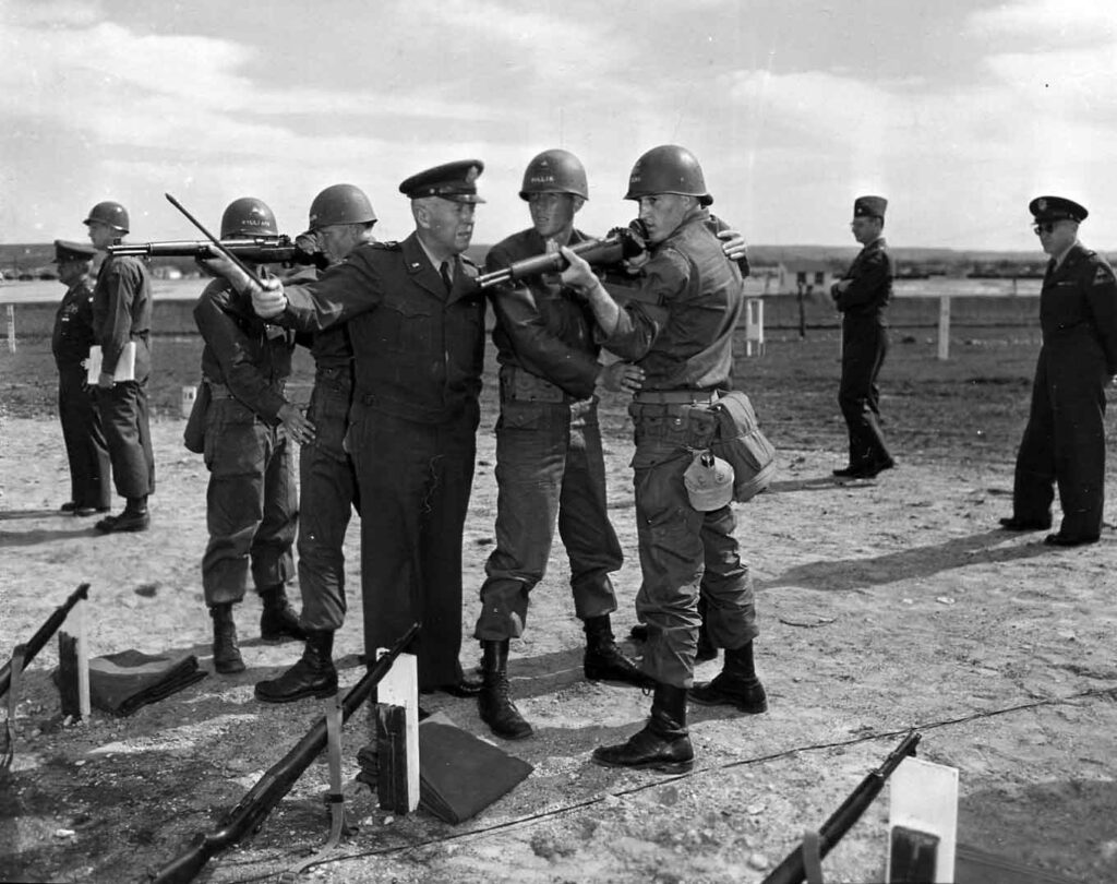 Major General Clarke, commanding general of the 1st Armored Division, advises a trainee on the use of an M1 Garand at Fort Hood, Texas, 18 March 1953. (National Archives)