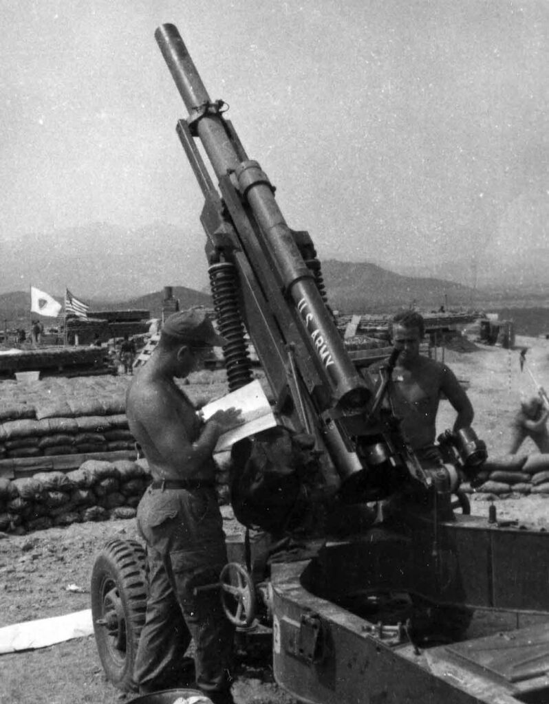 A soldier assigned to a field artillery battery of the Americal Division reads a technical manual on the M102 before test firing it at LZ Buff, 2 April 1969. (National Archives)