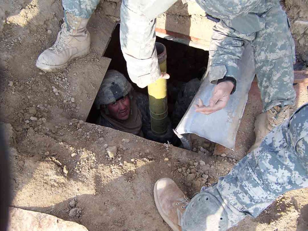 A soldier lifts enemy munitions out of a captured underground weapons cache in Diyala Province in November 2006. (Craig Honbarger)