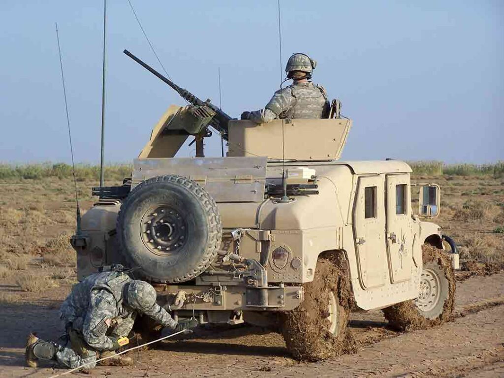 A 5-73 CAV trooper hooks up a tow cable to an up-armored Humvee armed with an M2 .50 caliber machine gun. (Craig Honbarger)