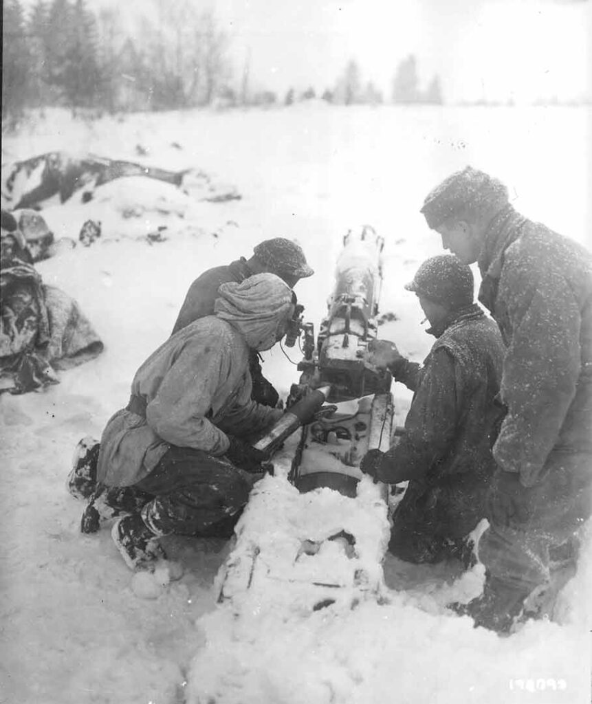 A gun crew from Battery B, 376th Parachute Field Artillery Battalion, loads their 75mm pack howitzer during fighting in Ardennes. (National Archives) 