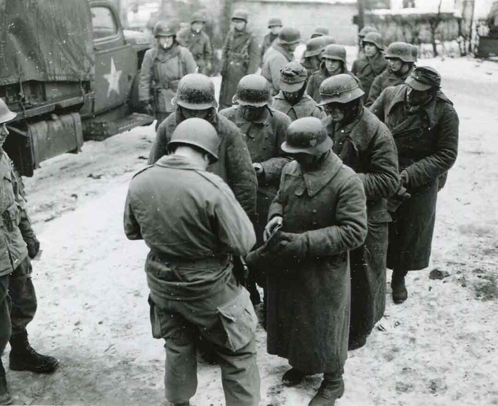 A paratrooper from the 505th PIR searches German prisoners for weapons before they enter a prisoner of war (POW) stockade. (National Archives) 