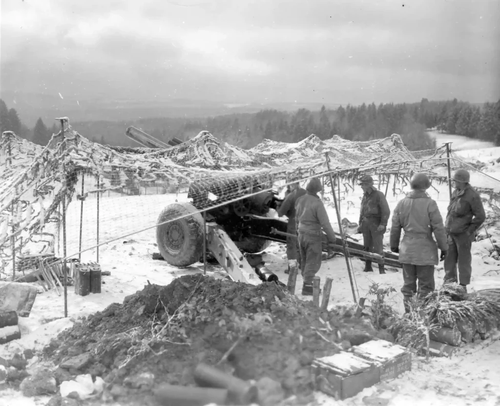 Snow falls on the camouflage net of a 155mm M1 Howitzer of the 254th Field Artillery Battalion, firing in support of the 82d Airborne Division at Werbomont, Belgium, 22 January 1945. (National Archives)